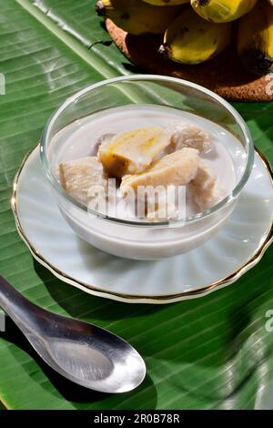 Banane in Kokosmilch. Traditionelle thailändische Desserts in einer Schüssel auf einem Bananenblatt mit Banane. Stockfoto