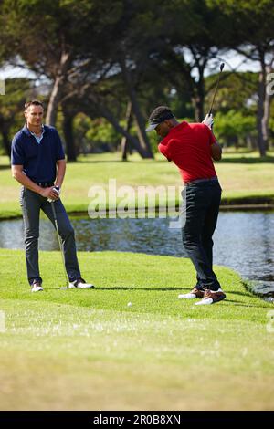 Zeit für einen großen Schwung. Zwei Männer spielen eine Runde Golf zusammen. Stockfoto