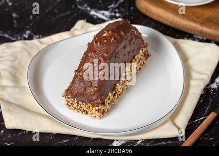 Bananen und Schokoladenkuchen. Schokoladenüberzug und Haselnuss-malaga-Kuchen auf dunklem Hintergrund. Stockfoto