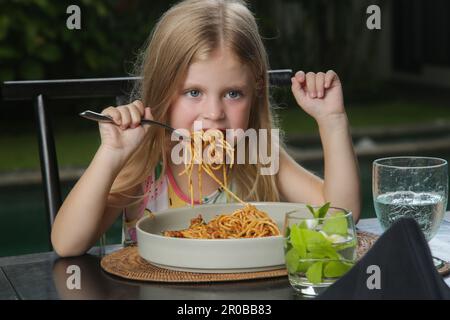 Ein kleines Mädchen isst Spaghetti Bolognese im Restaurant Stockfoto