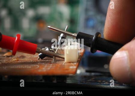 Elektrotechniker prüft elektronische Bauteile auf der Leiterplatte. Auf Diode fokussiert. Stockfoto