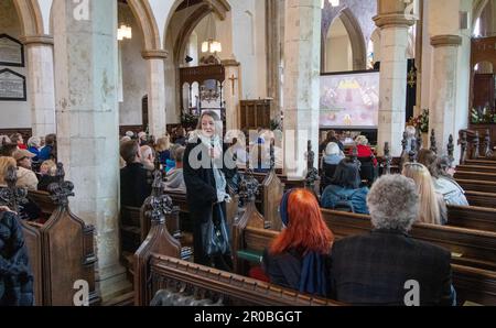 Die Leute saßen in der St.-Michaels-Kirche Framlingham Suffolk und sahen die Krönung von König Karl III. Auf einem großen Fernsehbildschirm Stockfoto