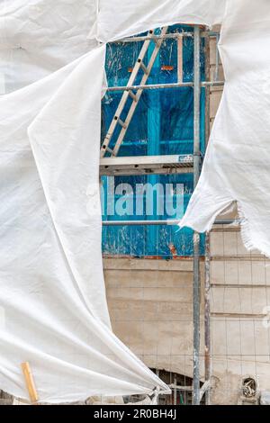 Das Fenster ist durch einen blauen Film geschützt, hinter dem Gerüst eines Gebäudes, das gerade repariert wird. Brüssel. Stockfoto