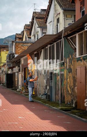 Selangor, Malaysia - 29. Oktober 2022 Tourist fotografiert die Wandbilder an den alten historischen Gebäuden in Kuala Kubu Bharu. Stockfoto