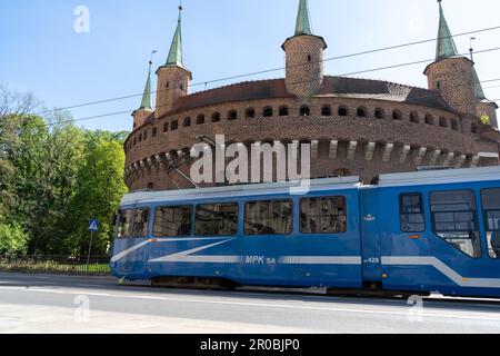 EU8N Straßenbahn neben dem Kraków Barbican, Barbakan Krakowski-Denkmal. Straßenbahn MPK Krakau Öffentliche Verkehrsmittel auf der Basztowa Straße in Krakau, Polen. Stockfoto