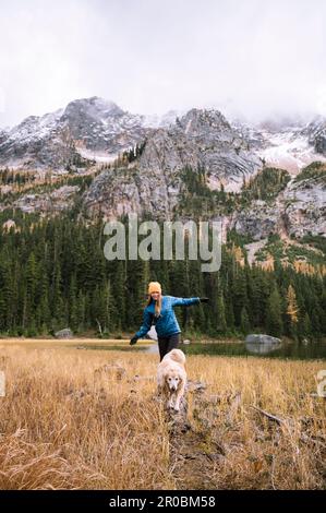 Ein Mädchen mit ihrem Hund wandert in den Bergen mit Herbstlarchen Stockfoto