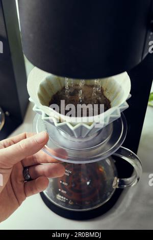 A Gießen Sie Wasser über die Maschine, und gießen Sie frisch gemahlenen Kaffee. Stockfoto