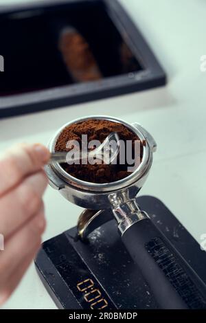 Frisch gemahlener Espresso wird auf einer Skala gemessen. Stockfoto