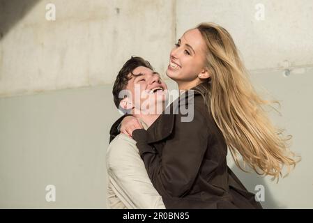 Junger Mann, der seine Freundin hochhebt und lächelt, München, Bayern, Deutschland Stockfoto