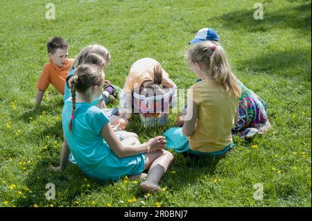 Ein Mädchen, das Apfel mit dem Mund aus einem Eimer nehmen will, München, Bayern, Deutschland Stockfoto