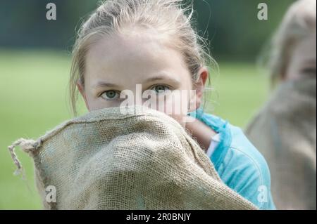 Nahaufnahme von Mädchen, die sich nach dem Sackrennen im Sack verstecken, München, Bayern, Deutschland Stockfoto