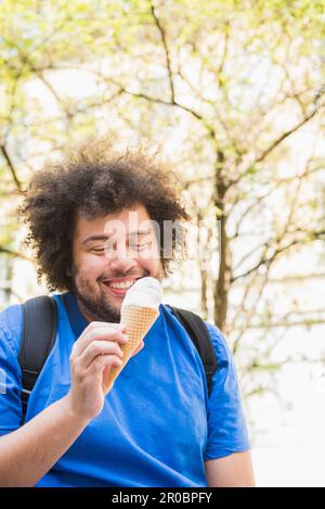 Glücklicher junger Mann, der Eis isst Stockfoto