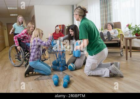 Mädchen, die mit Krankenschwestern und Seniorinnen im Altersheim Bowling spielen Stockfoto