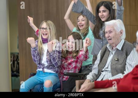 Mädchen feiern Erfolg mit Seniorinnen im Heim Stockfoto
