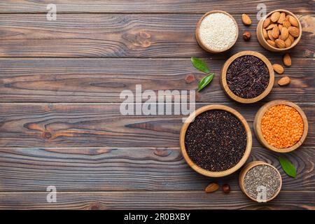 Verschiedene Superfoods in der kleinen Schüssel auf farbigem Hintergrund. Superfood wie Reis, Chia, Quinoa, Linsen, Nüsse, Sesamsamen, Mandeln. Kopierbereich der Draufsicht. Stockfoto