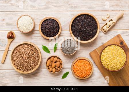 Verschiedene Superfoods in der kleinen Schüssel auf farbigem Hintergrund. Superfood wie Reis, Chia, Quinoa, Linsen, Nüsse, Sesamsamen, Mandeln. Draufsicht. Stockfoto