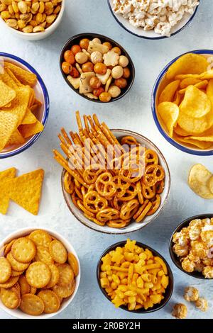 Salzige Snacks, Partymischung. Eine Auswahl knuspriger Vorspeisen, von oben geschossen. Tortilla und Kartoffelchips, Cracker, Popcorn usw. Stockfoto