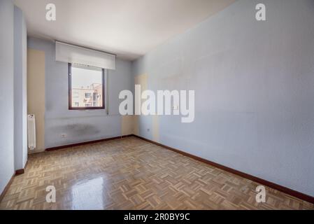 Ein leerer Raum mit Damast-Parkettboden, rotem Aluminiumfenster und weich-weißen Jalousien Stockfoto