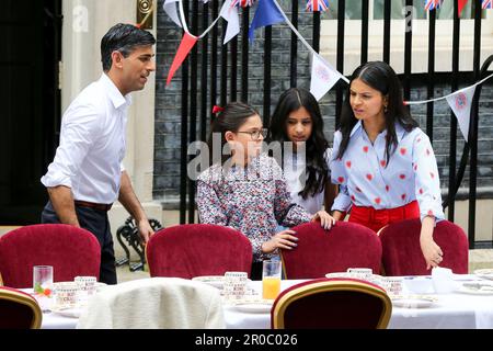 London, UK, 7. Mai 2023. Premierminister Rishi Sunak (L) und seine Frau Akshata Murty (R) und die Töchter Krishna Sunak (2. von L), Anoushka Sunak (2. von R) und der Familienhund Nova kommen aus nicht 10 heraus, um die Gäste zu begrüßen. Premierminister Rishi Sunak und seine Frau Akshata Murty veranstalten in der Downing Street, Westminster, ein großes Krönungsessen für Mitglieder der Gemeinde, Wohltätigkeitsorganisationen, Freiwillige und Menschen aus der Ukraine, die nach dem Ausbruch der russischen Invasion im Vereinigten Königreich leben. Die Nation feiert weiterhin die Krönung von König Karl III. Und Königin Camilla am 6. MJ 2023 als Big Cor Stockfoto