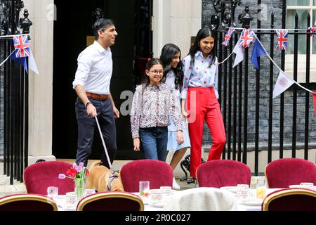 London, UK, 7. Mai 2023. Premierminister Rishi Sunak (L) und seine Frau Akshata Murty (R) und die Töchter Krishna Sunak (2. von L), Anoushka Sunak (2. von R) und der Familienhund Nova kommen aus nicht 10 heraus, um die Gäste zu begrüßen. Premierminister Rishi Sunak und seine Frau Akshata Murty veranstalten in der Downing Street, Westminster, ein großes Krönungsessen für Mitglieder der Gemeinde, Wohltätigkeitsorganisationen, Freiwillige und Menschen aus der Ukraine, die nach dem Ausbruch der russischen Invasion im Vereinigten Königreich leben. Die Nation feiert weiterhin die Krönung von König Karl III. Und Königin Camilla am 6. MJ 2023 als Big Cor Stockfoto