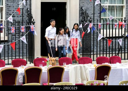 London, UK, 7. Mai 2023. Premierminister Rishi Sunak (L) und seine Frau Akshata Murty (R) und die Töchter Krishna Sunak (2. von L), Anoushka Sunak (2. von R) und der Familienhund Nova kommen aus nicht 10 heraus, um die Gäste zu begrüßen. Premierminister Rishi Sunak und seine Frau Akshata Murty veranstalten in der Downing Street, Westminster, ein großes Krönungsessen für Mitglieder der Gemeinde, Wohltätigkeitsorganisationen, Freiwillige und Menschen aus der Ukraine, die nach dem Ausbruch der russischen Invasion im Vereinigten Königreich leben. Die Nation feiert weiterhin die Krönung von König Karl III. Und Königin Camilla am 6. MJ 2023 als Big Cor Stockfoto