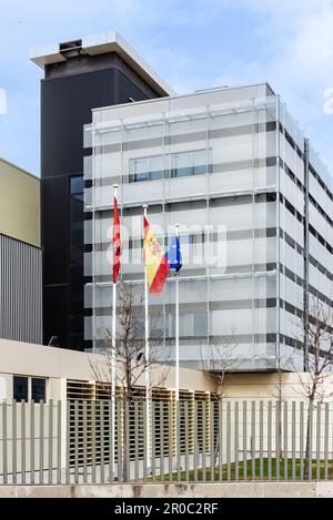 Fassade des Industrie- und Bürogebäudes mit mehreren Fahnenmasten, die mit Flaggen im Wind winken Stockfoto