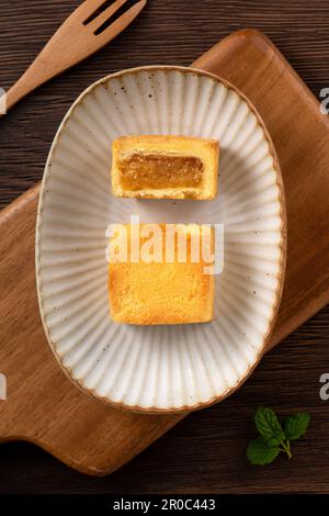 Köstliches taiwanesisches berühmtes Ananaskuchen Gebäck als Dessert auf einem Teller auf einem Holztisch mit heißem Tee. Stockfoto