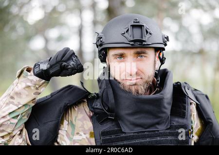 Ein junger Soldat in Uniformen und taktischer Weste arbeitet im Wald und bereitet sich auf die Aktion an einem temporären Waldstützpunkt vor. Ein Mann tut es bei der Minenräumung Stockfoto