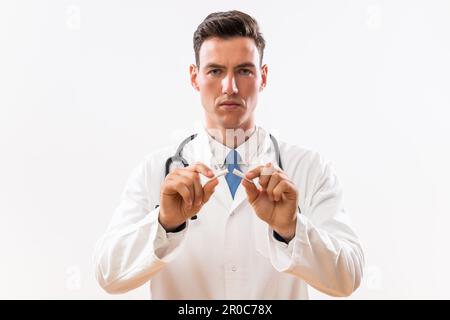 Bild eines Arztes, der eine kaputte Zigarette zeigt. Rauchverbot-Konzept. Stockfoto