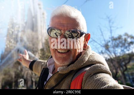 Attraktiver Mann mittleren Alters, der die Sagrada Familia in Barcelona besucht - glücklicher Tourist, der ein Selfie auf der Straße macht - Tourismus- und Urlaubskonzept Stockfoto