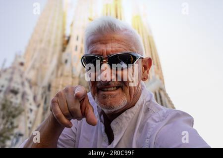 Attraktiver Mann mittleren Alters, der die Sagrada Familia in Barcelona besucht - glücklicher Tourist, der ein Selfie auf der Straße macht - Tourismus- und Urlaubskonzept Stockfoto