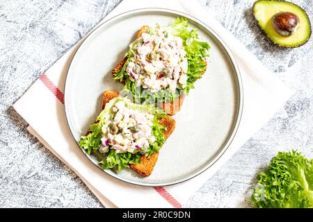 Schrittweise Zubereitung eines Sandwichs mit Thunfisch, Avocado, Gurke und Zwiebel Stockfoto