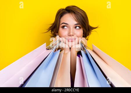 Porträt von reizenden weiblichen Händen halten Ladentaschen sehen leer aus, isoliert auf gelbem Hintergrund Stockfoto