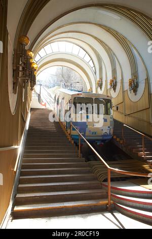 Eine blau-weiße Seilbahn steigt auf Schienen entlang der Steigung. Seilbahn, Seitenansicht. Station Kiew, Ukraine Stockfoto