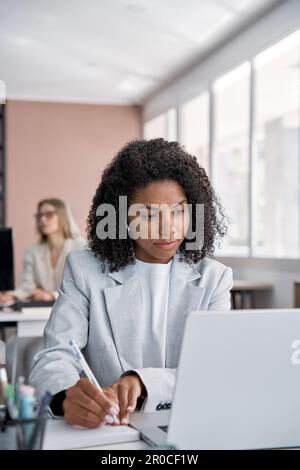 Junge Geschäftsfrau, erfolgreiche Unternehmerin, die App-Gadget verwendet und Notizen schreibt Stockfoto