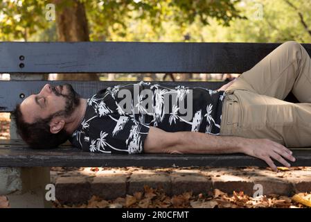 Ein Mann, der auf einer Bank im Park schläft Stockfoto