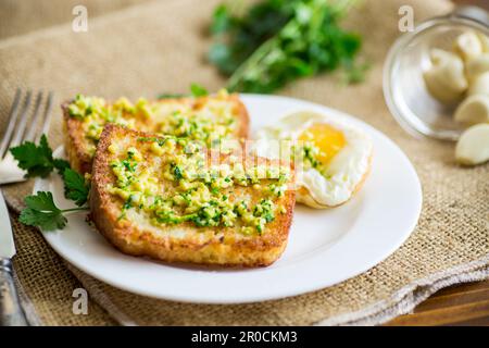 Gebratene Croutons in Teig mit Knoblauch und Kräutern auf einem Teller, auf einem Holztisch. Stockfoto