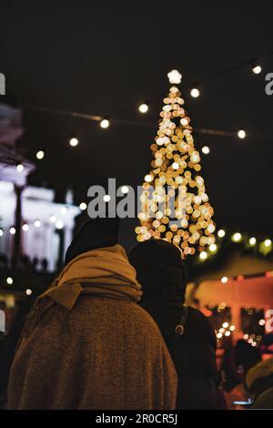 Zwei Frauen, die auf den großen Weihnachtsbaum zugehen und die Weihnachtszeit genießen Stockfoto