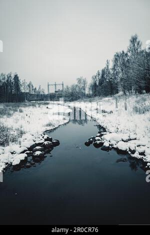 Eine malerische Winterszene mit einem gewundenen Bergbach und unberührtem weißen Schnee in der umliegenden Landschaft Stockfoto