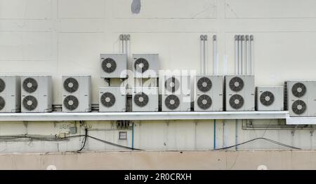 Viele Kondensatoren von Klimaanlagen sind an Betonbauwänden installiert. Wartungs- und Reparaturservice für Klimaanlagen zu Hause oder im Büro. Stockfoto