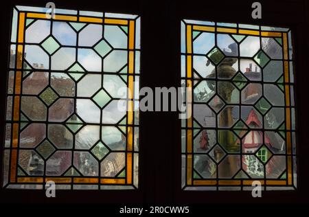 Rouen, Frankreich: Blick durch zwei Buntglasplatten in einem oberen Stockwerk des Gros Horloge Museums auf die Dächer des historischen Stadtzentrums. Stockfoto