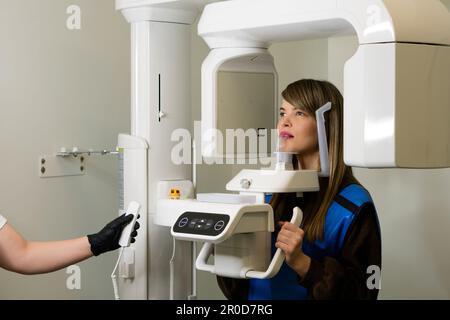Der Röntgentechniker macht einen CT-Scan der Kiefer-Patientin. Frau mit kreisförmigem Kieferschnappschuss in der modernen Zahnheilkunde. Computertomographische 3D-Tomographie der Zähne. Pano Stockfoto