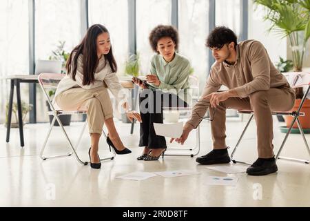 Drei Multiethnische Kollegen, Die Sich Ein Brainstorming Mit Papers Im Amt Anschauen Stockfoto