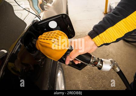Die Hand eines Mannes betankt das Auto mit einer gelben Pumpe, Nahaufnahme Stockfoto