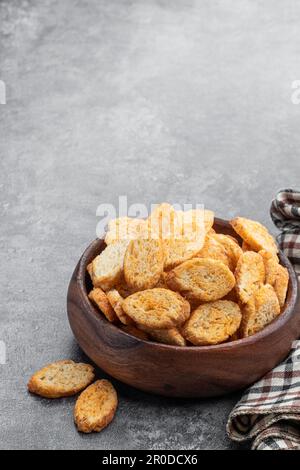 Knusprige Croutons in Holzschüssel auf grauem Hintergrund Stockfoto