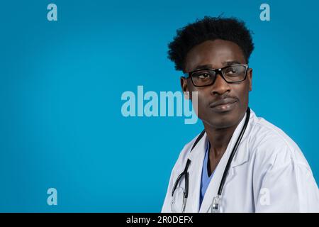 Nahaufnahme eines gutaussehenden afrikanischen Arztes mit Brille, blauer Hintergrund Stockfoto