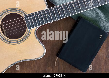 Gitarre- und bibelbuch auf Holzhintergrund, Blick von oben. Stockfoto