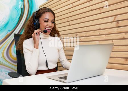 Ein schöner junger Callcenter-Agent lächelt in einer privaten, modernen Bürozelle Stockfoto