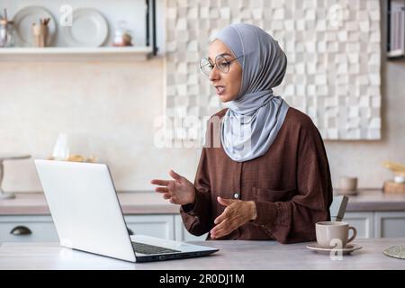 Online-Psychotherapiesitzung. Eine junge weibliche muslimische Psychologin in einem Hijab sitzt zu Hause vor einem Laptop und führt eine Ferntherapie-Beratung mit einem Patienten durch. Stockfoto