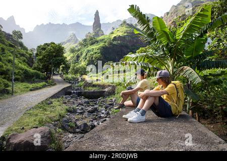 Touristen Muttersohn mit Blick auf Xoxo Dorf und Felsenmonolith in einem spektakulären üppigen Tal auf der Insel Santo Antao, Capo verde, Cabo verde Stockfoto